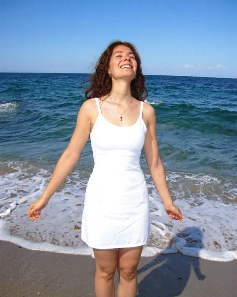 Mujer sonriendo frente al mar con los brazos abiertos