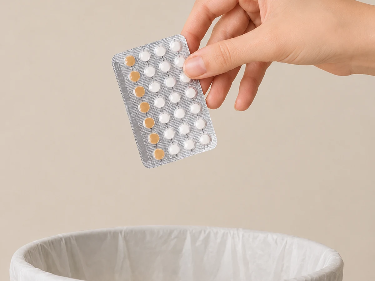 Mano sosteniendo un blíster de píldoras anticonceptivas sobre una papelera